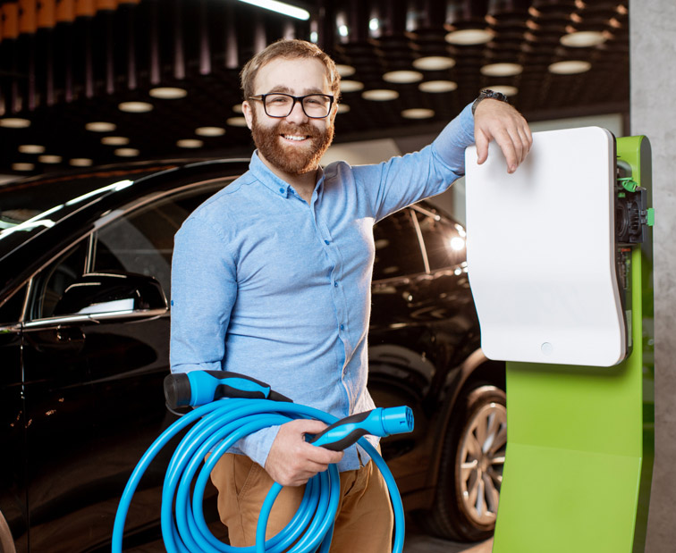 Mężczyzna trzymający ładowarkę do auta elektrycznego